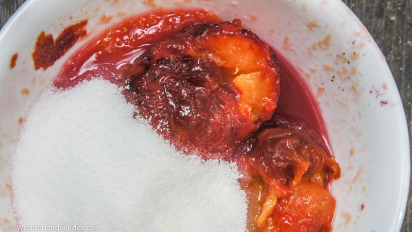 Adding sugar to mashed plums.